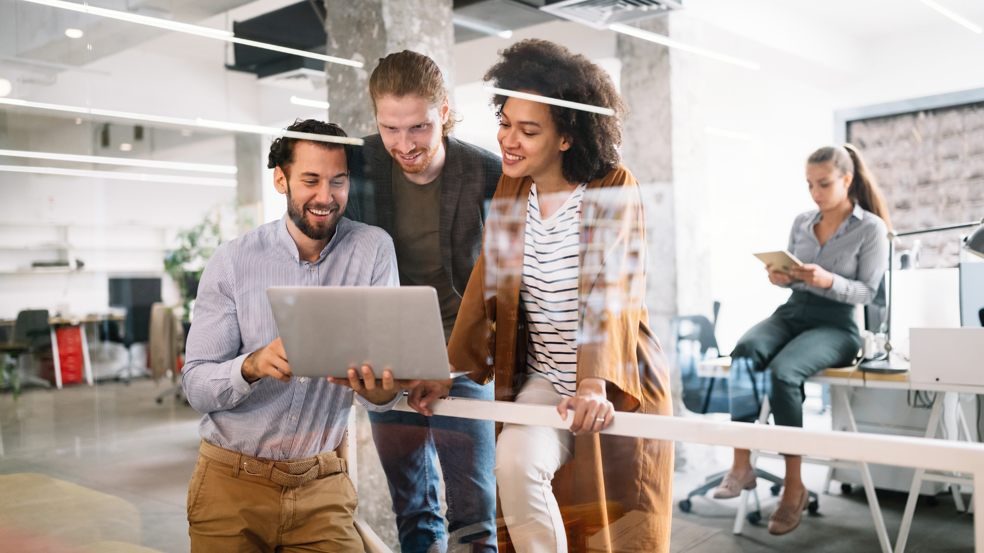 Three colleagues collaborate on a laptop in an office, discussing strategies for streamlining airline group sales.