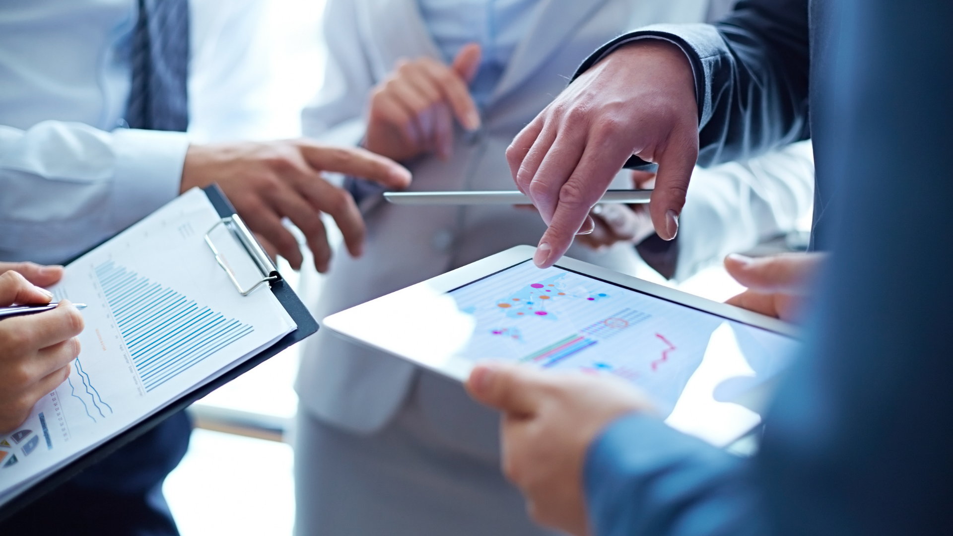 Business professionals collaborating on a tablet, discussing AI-driven group booking strategies for airline revenue growth.