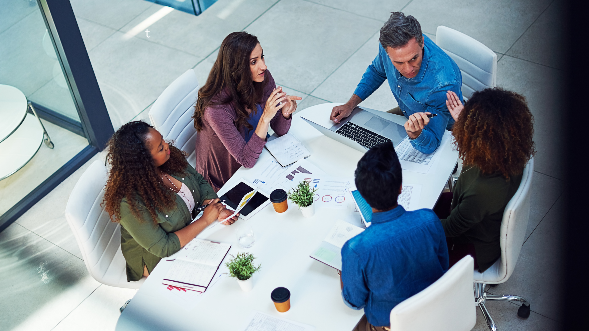 A group of people collaborating around a table with laptops, focused on improving group booking revenue through pricing insights.